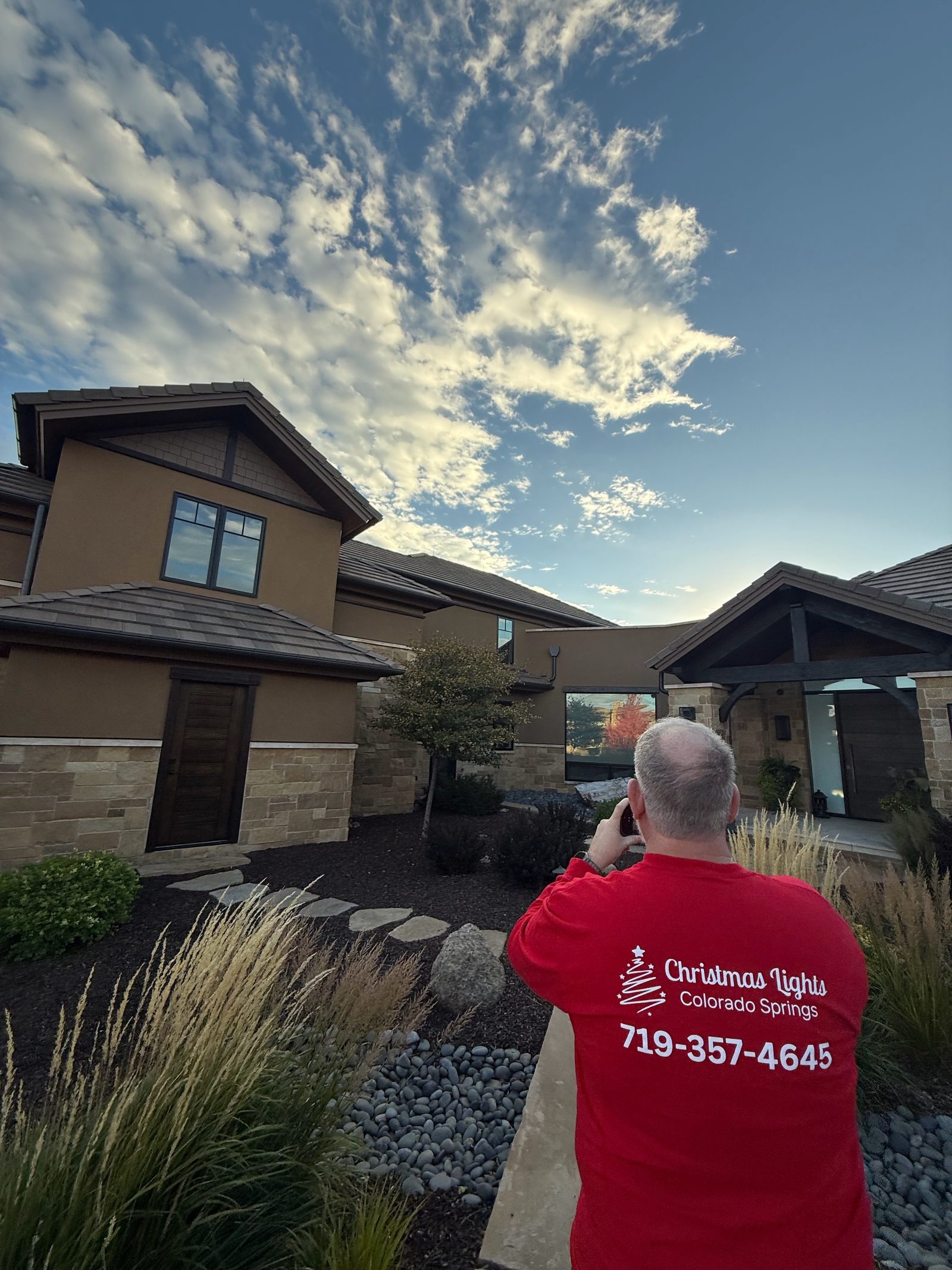 Company technician in branded shirt photographing a finished holiday lighting install