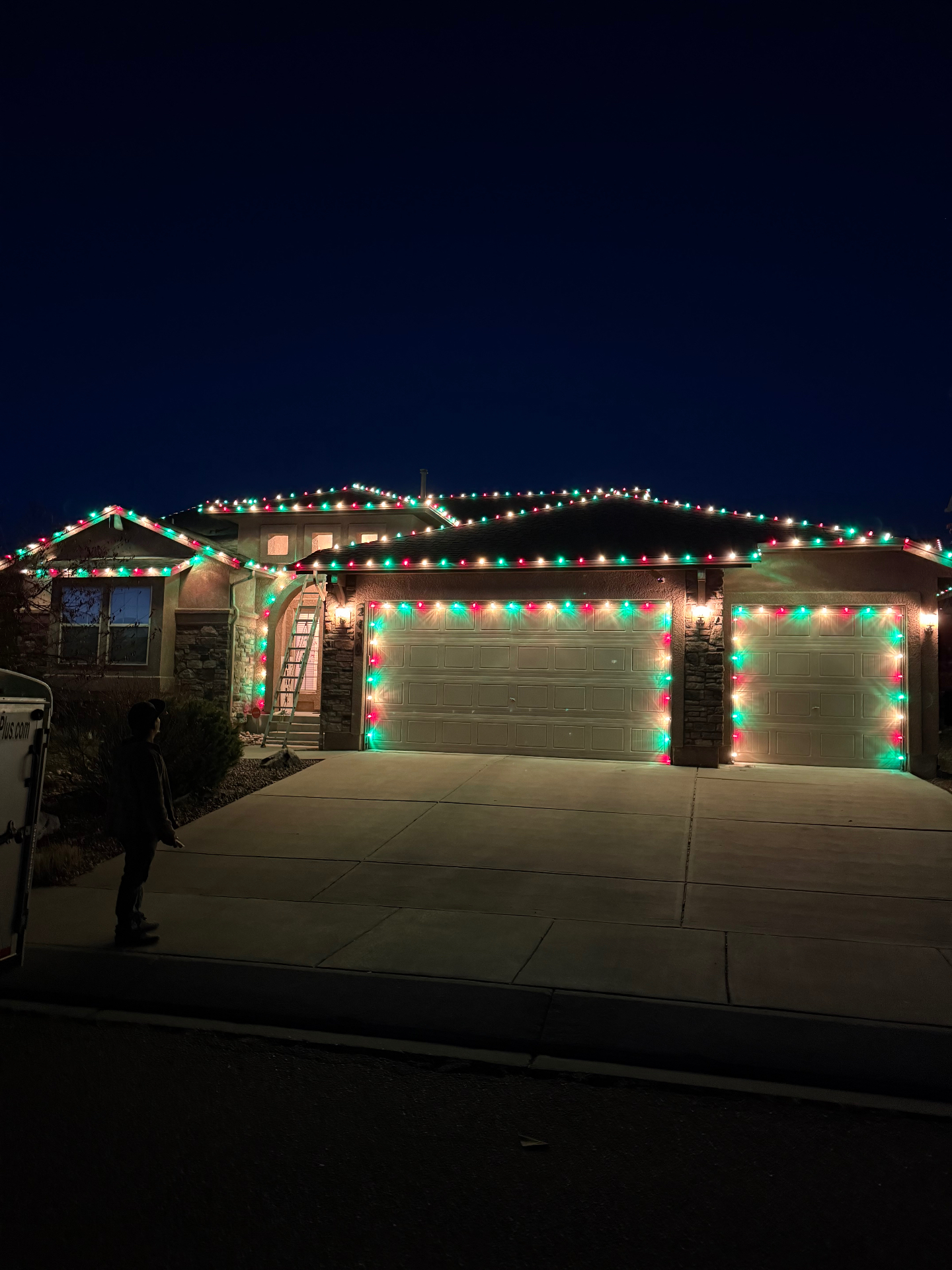 Red and green residential Christmas light installation across a home's roofline and garage on the Front Range