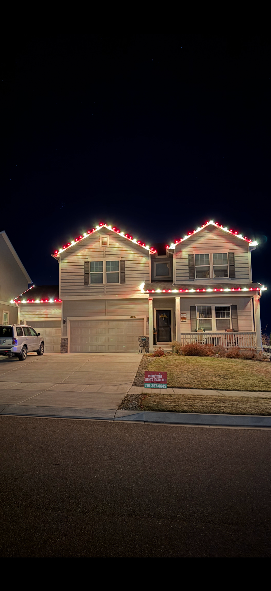 Red and white Christmas light installation on a two-story Front Range home's roofline and garage